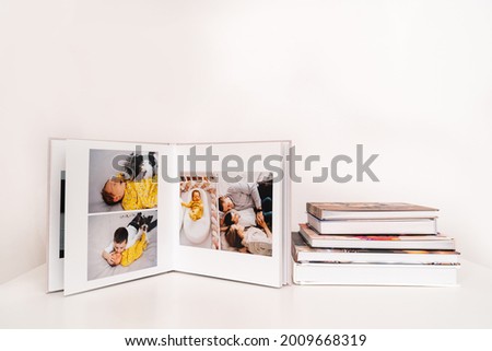 on white table open photobook from photo shoot of family with newborn baby. preservation of important moments of life in photo album. result of work of photographer and designer. polygraphy.
