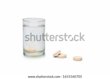 , on a white table pills, vitamins and a glass with effervescent vitamin water, isolate Imagine de stoc © 