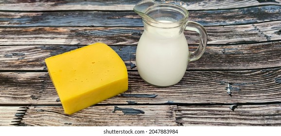 On a wooden background there are a piece of cheese and fresh cream in a decanter. Ukraine, September 26, 2021. - Powered by Shutterstock