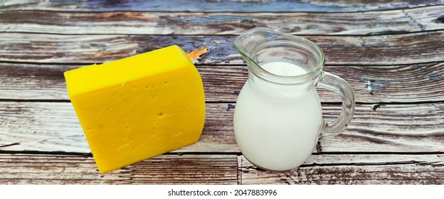 On a wooden background there are a piece of cheese and fresh cream in a decanter. Ukraine, September 26, 2021. - Powered by Shutterstock