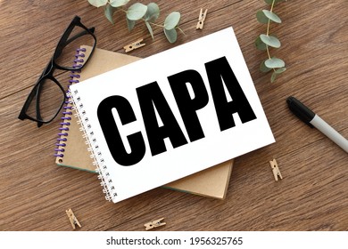 on a wooden background there are two notepads near glasses and a black felt-tip pen. Support Local. CAPA Corrective and Preventive action plans