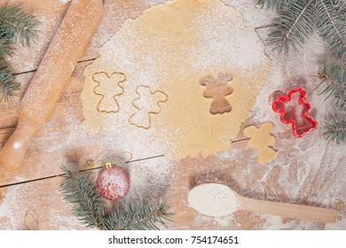 on a wooden board dough for Christmas cookies, rolling pin, branches of a Christmas tree, cookie shapes on a table, top view - Powered by Shutterstock