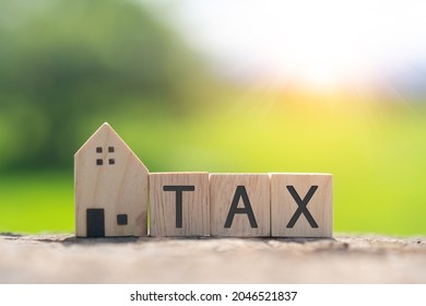 On A Wooden Cube Background, The Word Tax Appears. The Concept Of A Business Financial Loan Property.