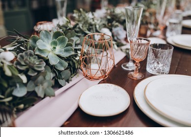 On The Wooden Long Banquet Table Are Glasses, Plates, Candles, The Table Is Decorated With Compositions Of Greenery And Eucalyptus Branches