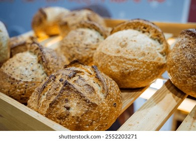 On a wooden shelf, there is a rustic wooden box that is completely filled with soft and fluffy bread rolls, providing a delightful visual display and a tempting aroma that fills the air - Powered by Shutterstock