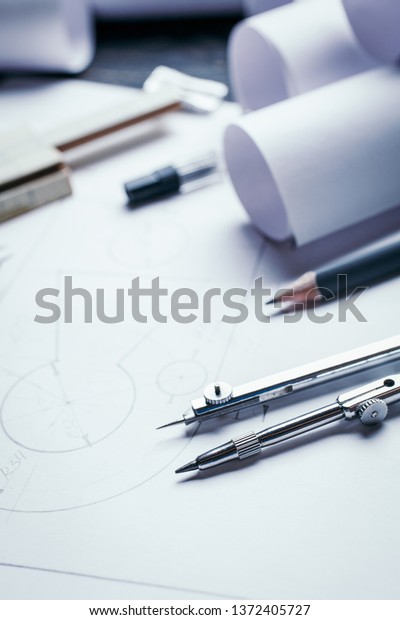 On a wooden table are drawings, compasses,\
pencil, ruler and sharpener. industrial drawing detail and several\
drawing tools. flat lay.