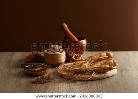 On the wooden table, ginseng root and medicinal herbs displayed on wooden tray with wooden mortar and pestle. Scene for medicine advertising, photography traditional medicine content