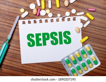 On a wooden table, a syringe, pills and a sheet of paper with the inscription SEPSIS. Medical concept