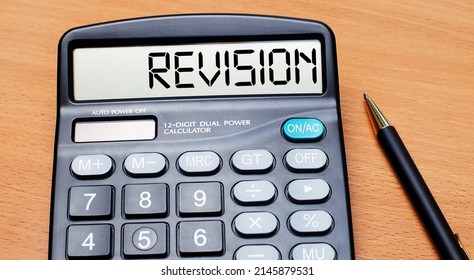 On A Wooden Table There Is A Black Pen And A Calculator With The Text REVISION. Business Concept