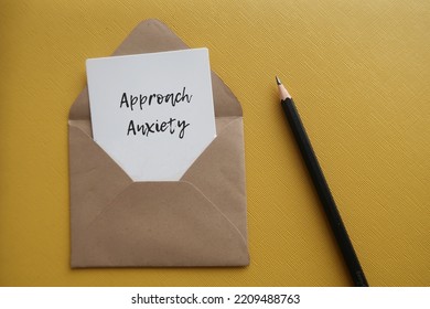 On yellow background, pencil and card in envelope with handwritten text Approach Anxiety - irrational fear of rejection which stop someone from engaging in conversation with strangers - Shutterstock ID 2209488763