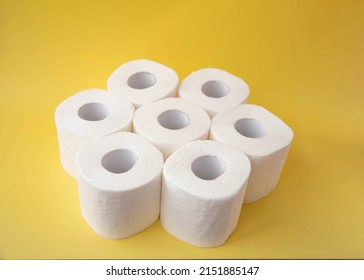 On A Yellow Background, Seven Rolls Of Toilet Paper Stand Side By Side