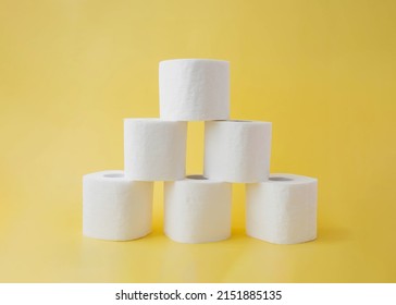 On A Yellow Background, Six Rolls Of Toilet Paper Stand In The Form Of A Pyramid