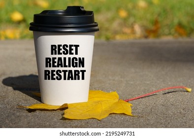 On A Yellow Maple Leaf There Is A Cup Of Coffee On Which Is Written - Reset, Realign, Restart. Business Concept.