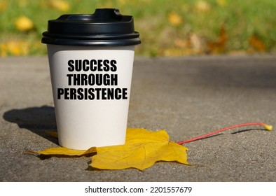 On A Yellow Maple Leaf There Is A Cup Of Coffee On Which Is Written - Success Through Persistence. Business Concept.