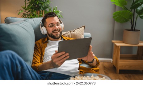 One adult man caucaian male on the sofa bed at home watch movie video online use digital tablet or have a video call - Powered by Shutterstock