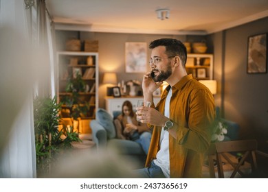 One adult man with eyeglasses stand at home use mobile phone talk - Powered by Shutterstock