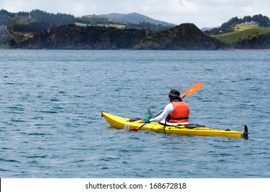 One Adult Man Rows A Yellow Sea Kayak In The Bay Of Island New Zealand A Very Popular Travel Destination In North;and In The North Island Of New Zealand. 