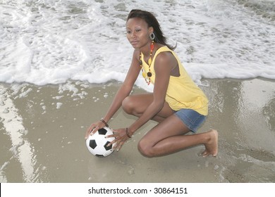 One African American Woman Holding A Soccer Ball Near The Surf At The Beach