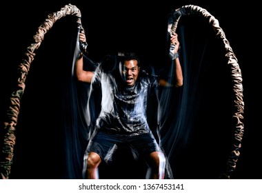 One Afro American Man Exercising Boot Camp Fitness Ropes Exercises Isolated On Black Background With Light Painting Speed Effect