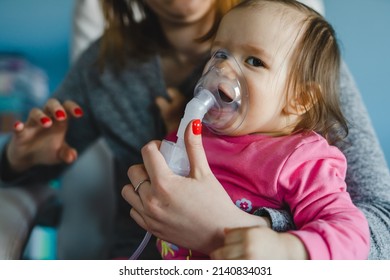 One Baby And Mother Using Nebulizer At Home Woman Hold Her Small Girl Child Using Vapor Steam Inhaler Mask Inhalation At Home Medical Procedure Medicament Treatment Asthma Pneumonia Bronchitis