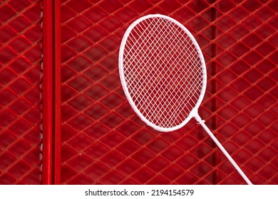 One Badminton Racket Is Hung On Red Grill By A Cable Tie For Display In Exhibition Sports Event