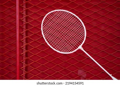 One Badminton Racket Is Hung On Red Grill By A Cable Tie For Display In Exhibition Sports Event