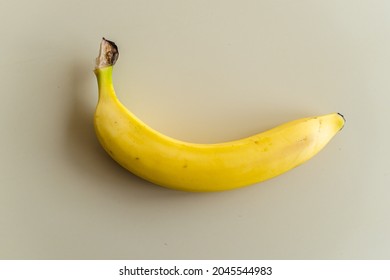 One Banana On A White Table. The Picture Was Taken Of An Imported Banana In Europe.