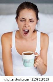 One Big YAWN. A Young Woman Giving A Big Yawn While Sitting With A Cup Of Coffee In Bed.