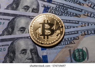 One Bitcoin on hundred dollars bills. Closeup, macro shot