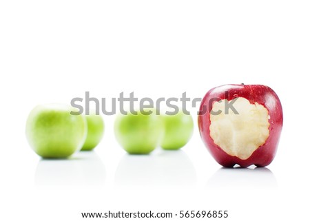 One bite red apple among green apples on white background.To be not like others.