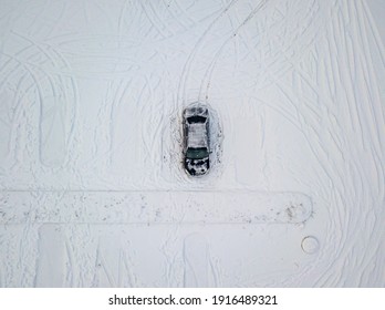 One Black Car In A Snow-covered Parking Lot. Aerial Drone View. Winter Snowy Morning.