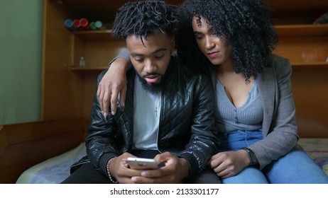 One Black Couple Looking At Cellphone Together In Bedroom