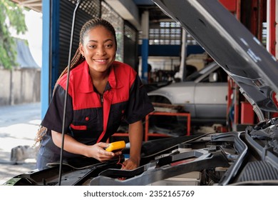 One Black female professional automotive mechanical worker checks an EV car battery and hybrid engine at a maintenance garage, expert electric vehicle service, and fixing occupations auto industry. - Powered by Shutterstock