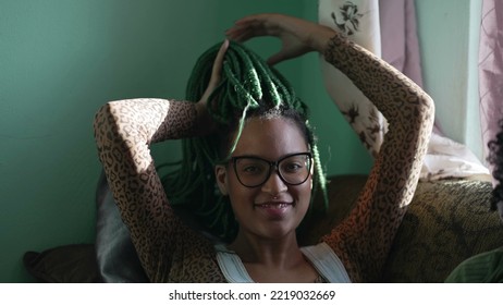 One Black Latina Adult Girl Playing With Braided Hairstyle. A Brazilian African American Young Woman Plays With Green Box Braid Hair At Home. Relaxed Emotion