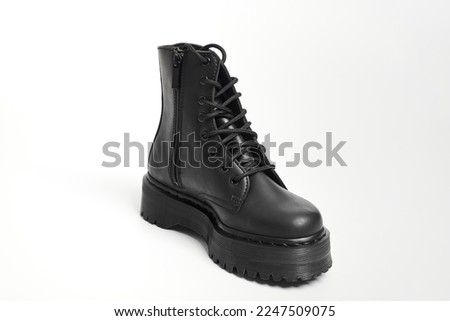 One black women combat boot on high heel platform with lug sole on isolated white background. Military stylish high heel platform combat shoe for woman leg, new footwear trend