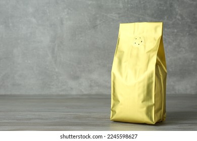 One blank foil package on wooden table against light grey background. Space for text