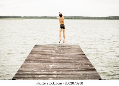 One Boy Jumping From Wooden Bridge Into Water, Rear View, Summer Time, Vacations