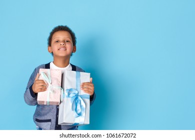 One Boy Studio Isolated On Blue Wall Celebration Concept Holding Gift Boxes Curious