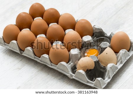 One broken egg in a container full of eggs.