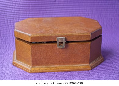 One Brown Closed Wooden Casket Box Stands On A Purple Table