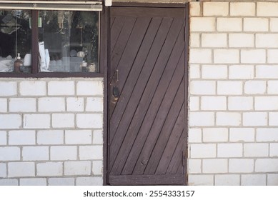 one brown closed wooden door on white brick wall with window of private house on rural street - Powered by Shutterstock