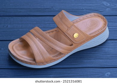 one brown leather summer sandal stands on black wooden floor - Powered by Shutterstock