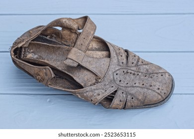 one brown old dirty leather sandal stands on the gray wooden floor in the room - Powered by Shutterstock