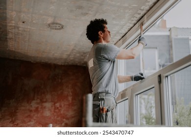One builder is measuring a window frame with a ruler.