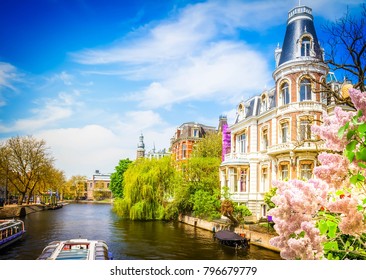 One of canals in Amsterdam old town, Netherlands with lilac flowers, toned