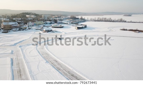 One car\
driving through the winter forest on country road. Top view from\
drone. Aerial view of snow covered road in winter, car passing by.\
Top view of the car traveling on snowy\
road