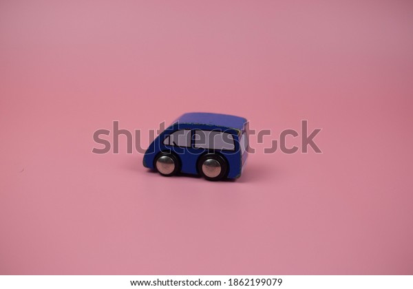 One car rests on a pink\
background.