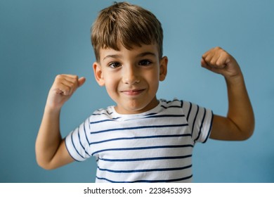 One caucasian boy child in front off blue wall at home goofing around indoor portrait childhood growing up concept - Shutterstock ID 2238453393