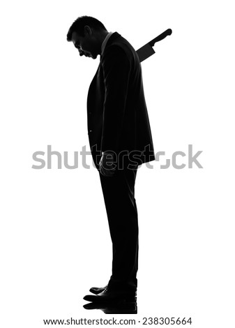 one caucasian business man Stabbed in the Back in silhouette on white background