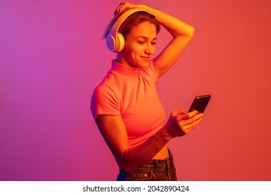 One caucasian girl in headphones putting hair up isolated over gradient background in neon lights  Music lifestyle  Concept human emotions  facial expression  beauty  Copy space for ad